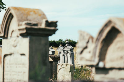 Cross in cemetery against sky