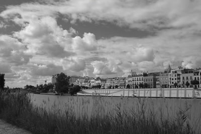 Buildings by river against sky in city