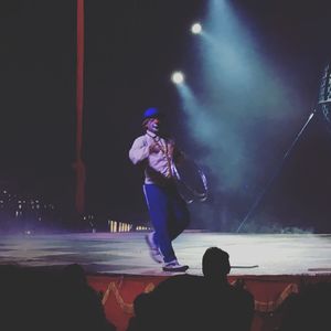 Rear view of man with arms outstretched at night