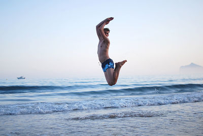 Rear view of jumping man at beach