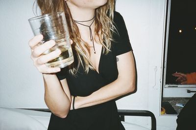 Midsection of young woman standing by drink