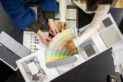 Businesswoman selecting color swatch with client at desk