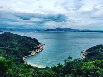 High angle view of sea and mountains against cloudy sky