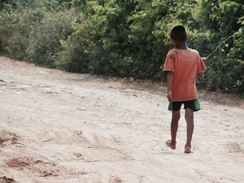 Rear view of boy walking on sand