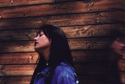 Young woman by wooden wall