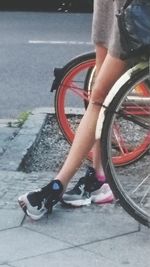 Low section of woman riding bicycle on street