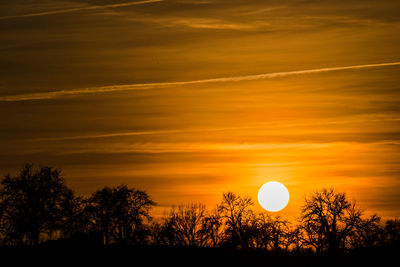 Silhouette trees on landscape against romantic sky at sunset