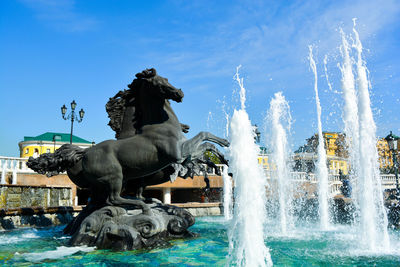 Statue by fountain against sky