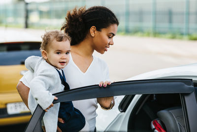 Young woman with girl entering car