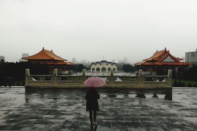 Rear view of man in traditional temple against sky