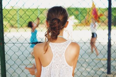 Woman standing in front of chainlink fence