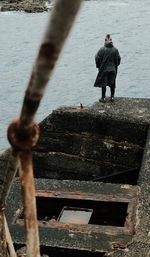 Rear view of man standing on railing