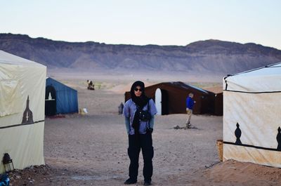 Full length portrait of beautiful young man standing in desert