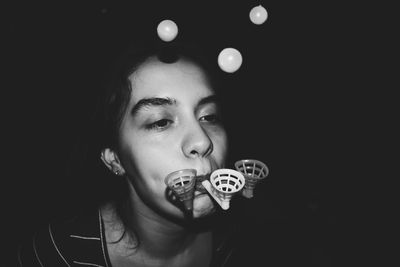Close-up of young woman holding camera over black background