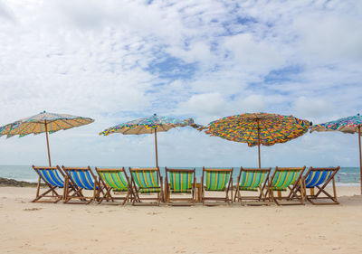 Chairs and parasols on beach against sky