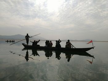 People in boat on lake against sky