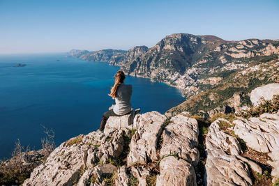 Rear view of man standing on mountain against sky