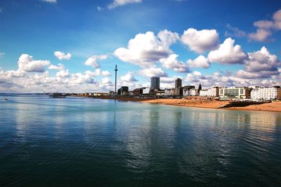 View of city at waterfront against cloudy sky