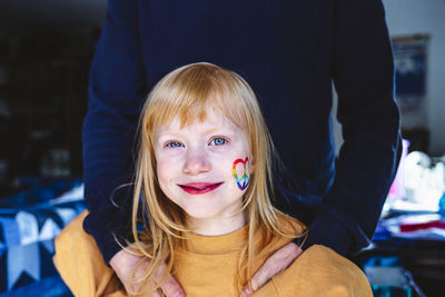 Cute smiling blond girl standing with father at home