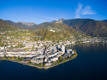 Aerial view of townscape by lake against blue sky