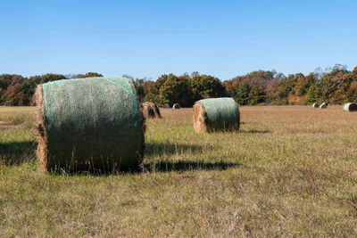 Hay bales on field against clear sky