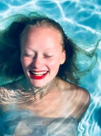 Smiling girl with eyes closed swimming in pool