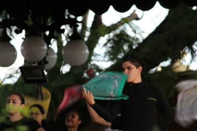 Rear view of young woman with balloons at trees