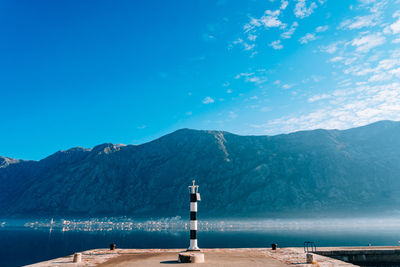 Scenic view of sea by mountains against blue sky