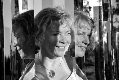 Close-up of smiling woman between mirrors looking away