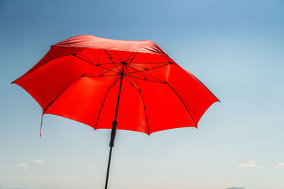 Low angle view of red umbrella against blue sky