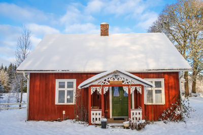 Idyllic red cottage with beautiful carpentry and snow in the garden