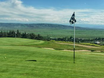 Scenic view of golf course against sky