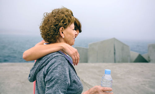 Mother and daughter standing on pier against sky