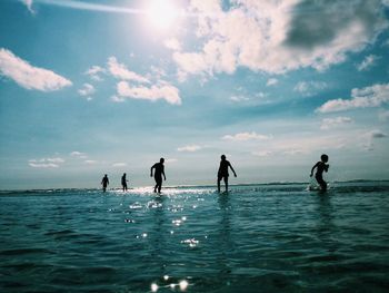 People enjoying in sea against sky on sunny day