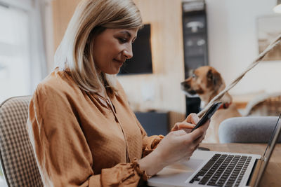 Businesswoman using mobile phone while sitting at home