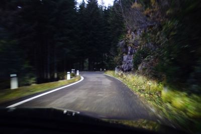 Road amidst trees seen through car windshield