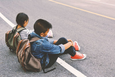 Full length of tired boy with sister relaxing on road