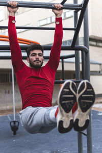 Young male athlete exercising on sports equipment on training ground in city