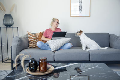 Woman on sitting on sofa with dog