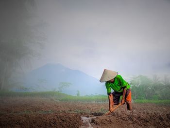 Man working on agricultural field against sky