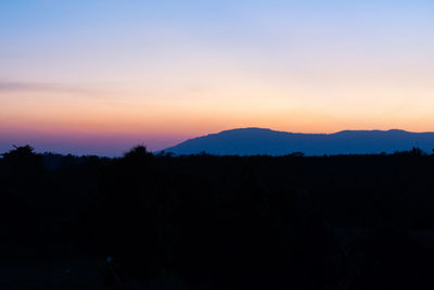 Scenic view of silhouette mountains against orange sky