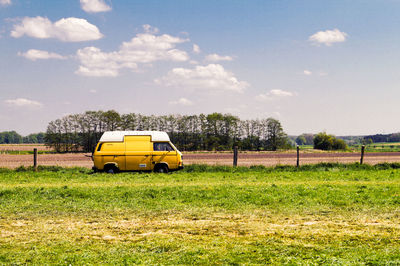 Yellow car on field against sky