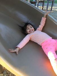 Portrait of happy girl enjoying on slide at park