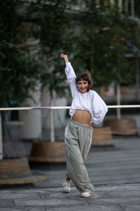 Full length of young woman standing on footpath