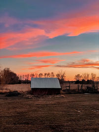 House on field against sky during sunset