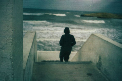 Rear view of man standing on staircase