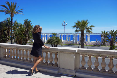 Full length of woman standing by railing against sky