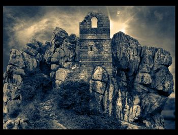 Low angle view of rock formation against cloudy sky