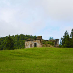 Abandoned building on field against sky