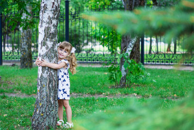 Girl standing on grass against trees